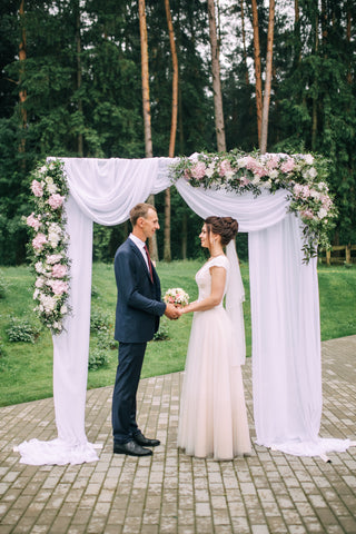 Wedding arch with flowers and fabrics.