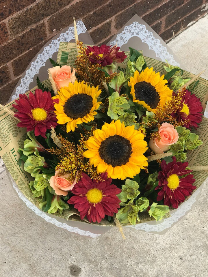 Bring the beauty of the outdoors in with this wildly wondrous bouquet, featuring the classic hues of autumn.  Includes:  Sunflowers, orange chrysanthemums, peach roses, solidago, yellow alstroemerias. Free message card