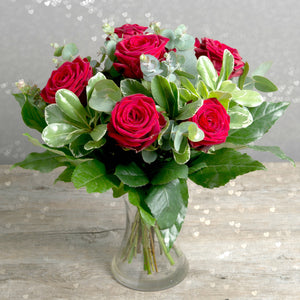 Lovely arrangement in a vase with 6 red roses and eucalyptus.