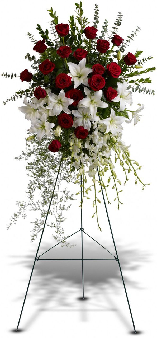 Funeral arrangement on holder with red roses, lylies and orchids.
