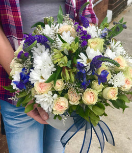 Like gazing into a clear blue sky, this serene arrangement soothes the soul and cheers the heart. Its creamy roses and snowy daisies are arranged in velvet box.  Includes:  White daisies, creamy mini roses, yellow alstroemerias, blue delphinium, blue veronica. Velvet box Free message card
