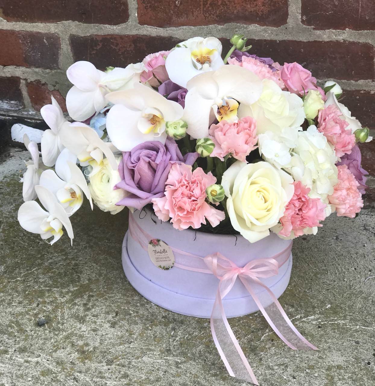 Go all out for love with this  white orchids, lavender roses and other fabulous favorites in a stylish velvet box. She will definitely be bowled over.  Includes:  Orchid, pink carnations, lavender and white roses, white ranunculus. Velvet box Free message card