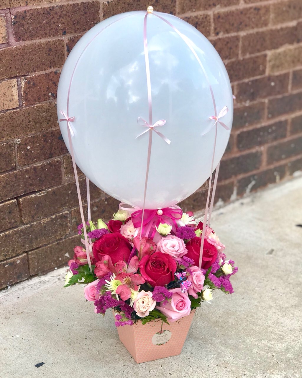 Welcome the newest little cutie into the world with this pink-tastic box. Decorated like air balloon, it's a darling little bundle - just like her.  Includes:  Pink roses, pink alstroemerias, white daisies, pink lisianthus, assorted greens. Balloon Floral box Free message card