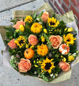 A burst of beauteous blooms in autumn shades of orange and yellow is mixed with a funny pumpkins. A splendid gift for birthdays or any fall occasion.  Includes:  Sunflowers, peach roses, white and yellow freesias, yellow snap dragons, assorted greens.  Artificial pumpkins Wrapped in a craft paper Free message card 