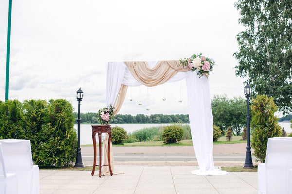 Many brides want their wedding ceremony to have a gorgeous and personalized backdrop, because it is in front of this arch that many magic and touching moments occur, and many memorable photos are taken. Wedding arch with flowers and fabrics. Includes: White chiffon fabrics Flowers: white chrysanthemums, pink hydrangea, assorted greens. Metal stand Dimensions: width 78'', height 86''