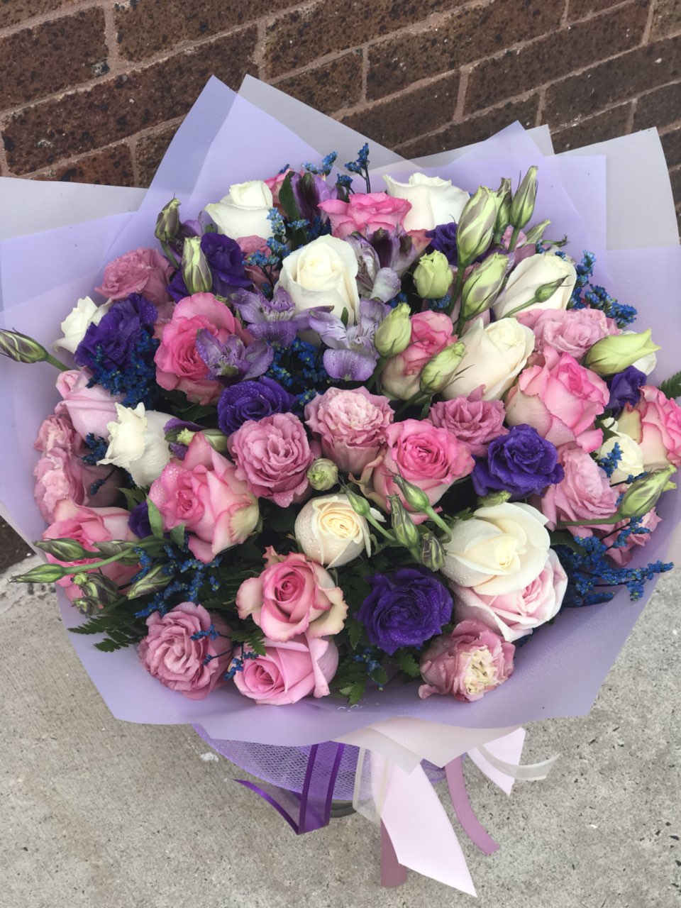 Whatever the occasion - when you truly want to spoil her, send this luxurious lavender arrangement! Deluxe and dramatic, this mix of flowers is a gift she won't soon forget.  Includes:  Pink roses, purple and pink lisianthus, white roses, blue limonium, fern. Wrapped in a craft paper Free message card