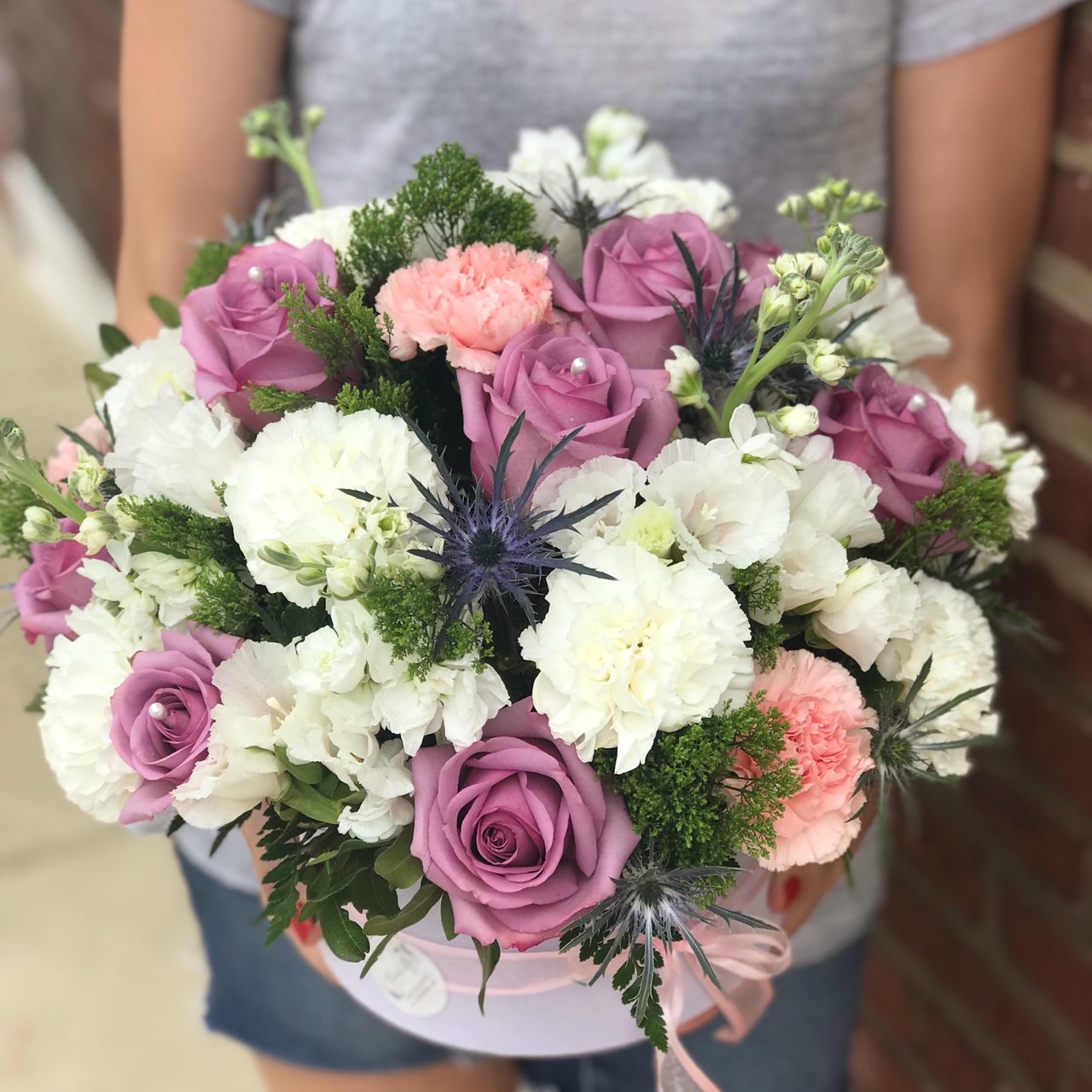 They'll fall in love with this pretty, playful bouquet!  It's a fresh mix they'll adore for any occasion.  Includes:  Purple roses, pink and white carnations, eringium, white stock, assorted greens. Velvet box Free message card