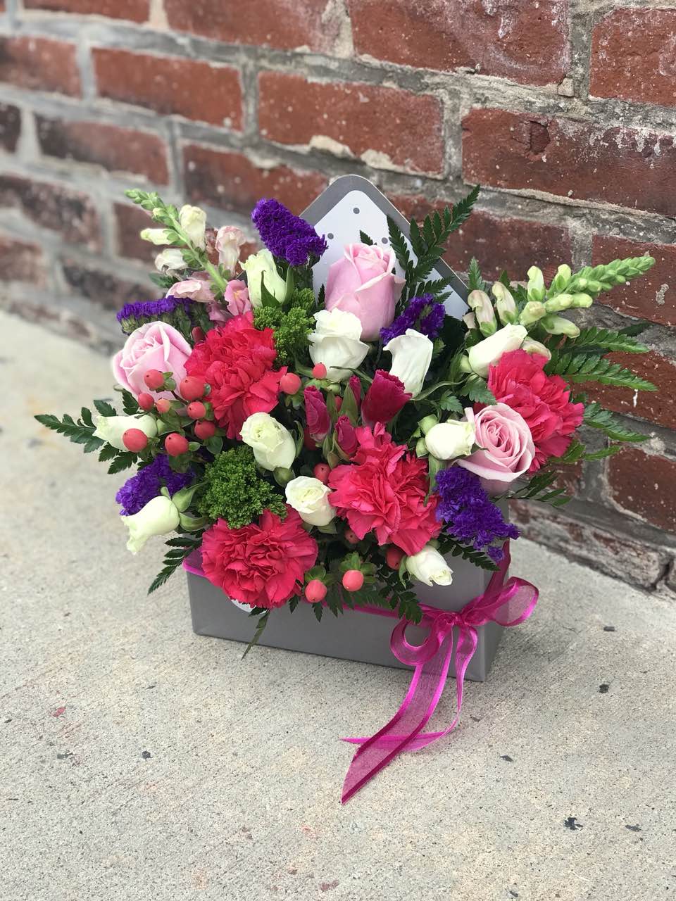 Show your romantic side by sending this gorgeous arrangement in a charming  envelope. She'll love the gift, and you for having such amazingly good taste. Includes: Hot pink carnations, pink roses, berries, snap dragons, purple stacice. Floral envelope. Free message card Available for same day delivery!