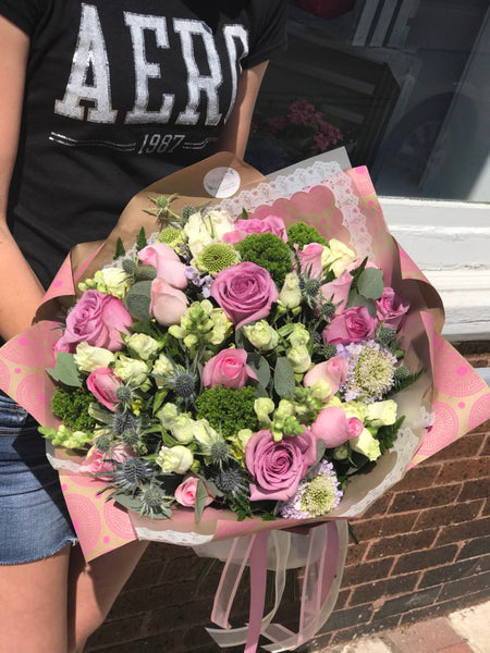 What's better than pink? More pink! It's an impressive gift that promises to put some pink in her cheeks!  Includes:  Lavender and pink roses, eringium, scabiosa, yellow snapdragons, assorted greens. Wrapping in craft paper Free message card